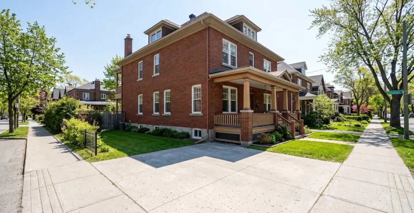 Façade extérieure d'une maison résidentielle en brique style années 1920 avec espace latéral dégagé, quartier résidentiel d'Outremont par temps ensoleillé
